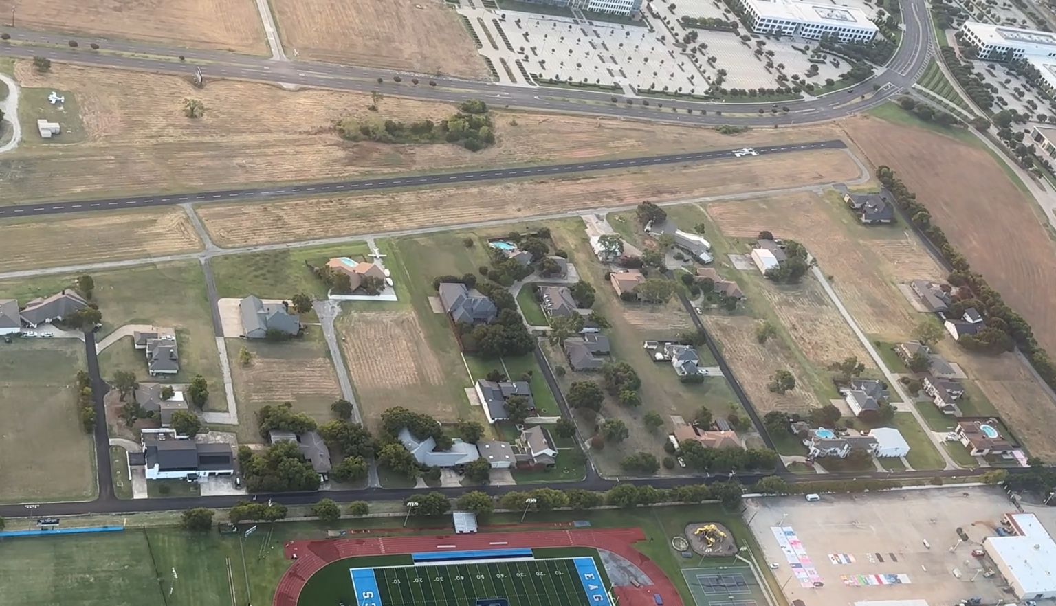 Aerial view of Air Park Dallas homes, hangars and taxiways beside the runway