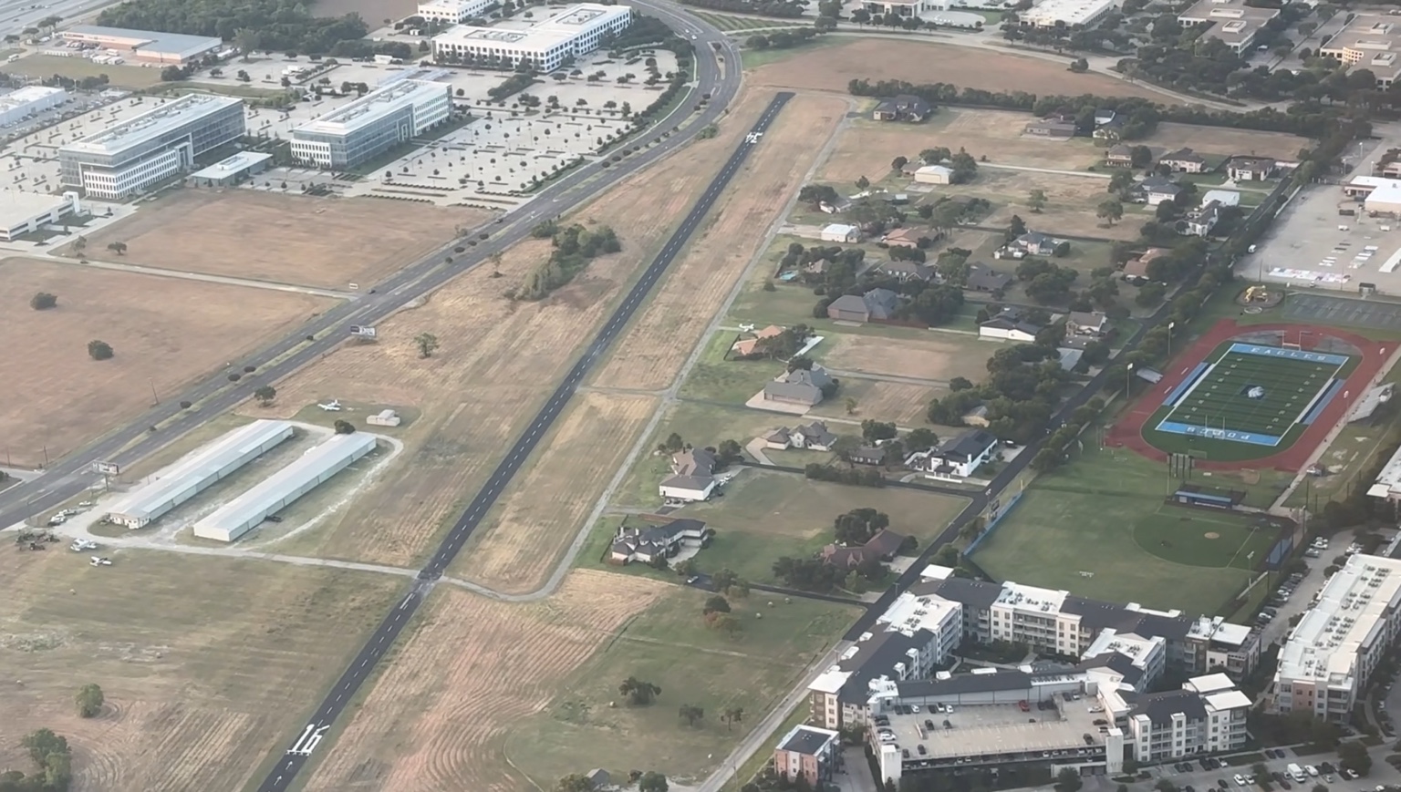 Aerial view of Air Park Dallas (F69), its runway, homes, hangars and urban setting