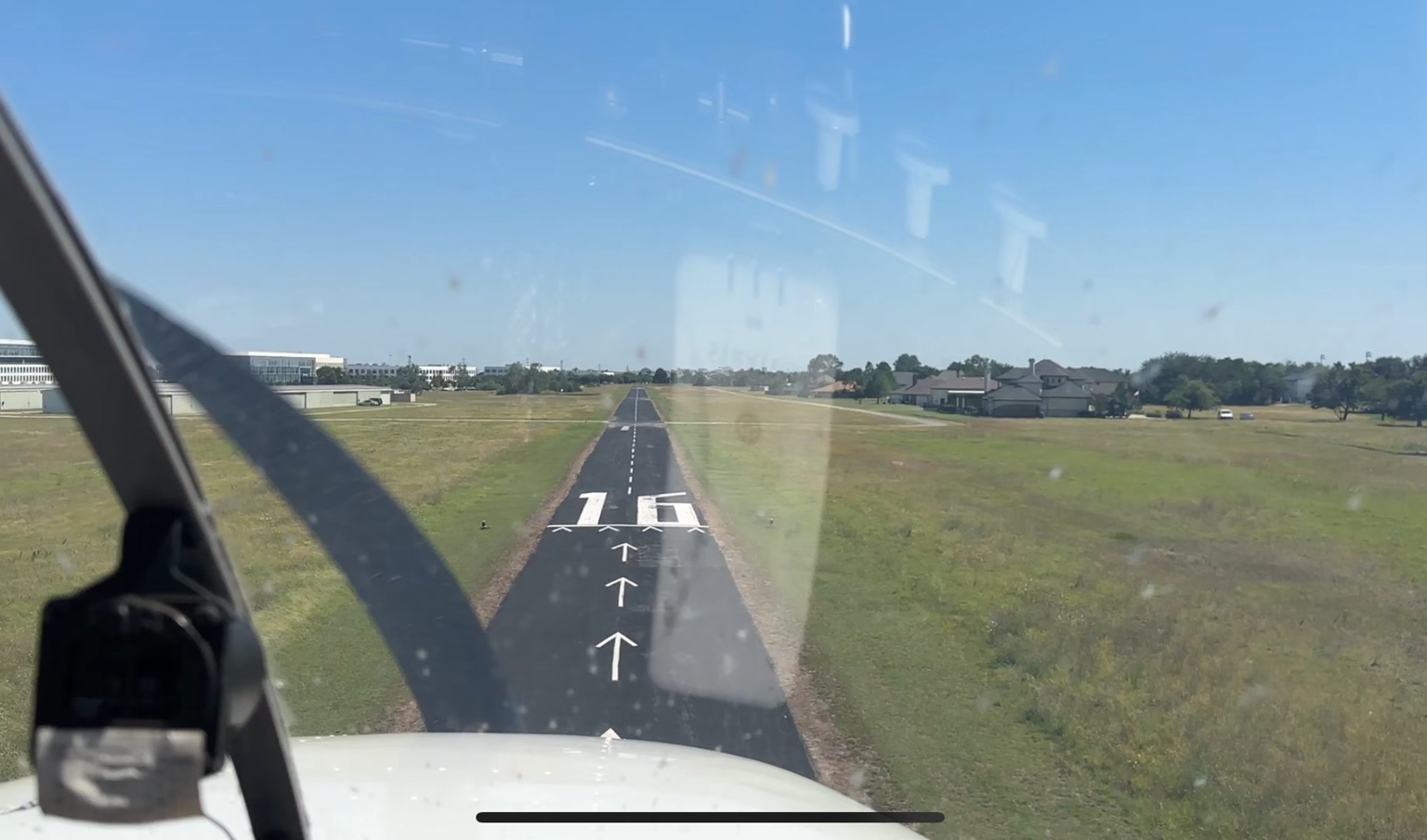Pilot's view on short final to Runway 16 at Air Park Dallas with homes and hangars alongside