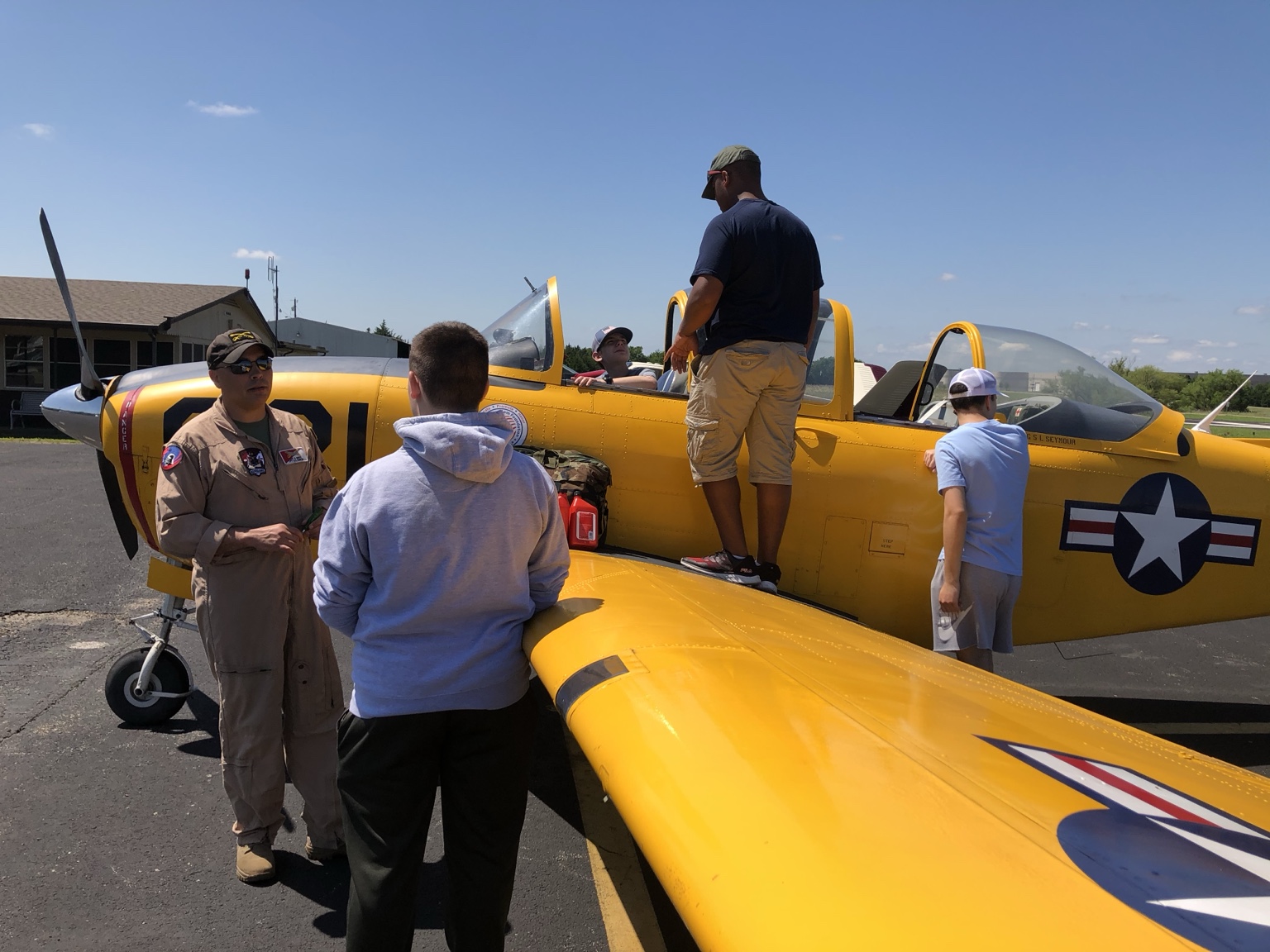 Young attendee learning about a yellow vintage aircraft at an Airplanes and Coffee event