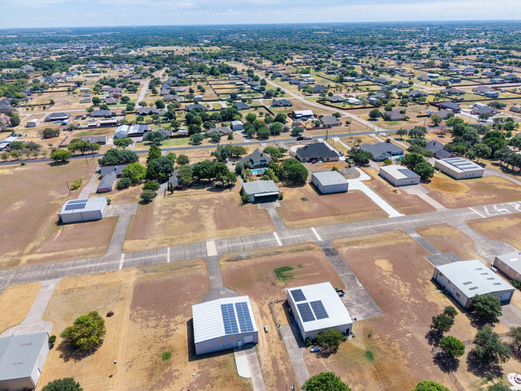 Wide aerial view across Eagle’s Nest Estates showing homes, private hangars and the community taxiway network