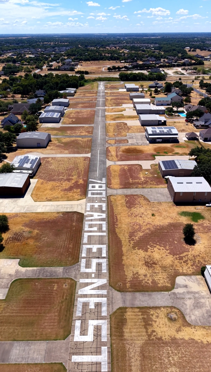 Aerial view of Eagle’s Nest Estates Airport (T56) with the community name painted beside the runway