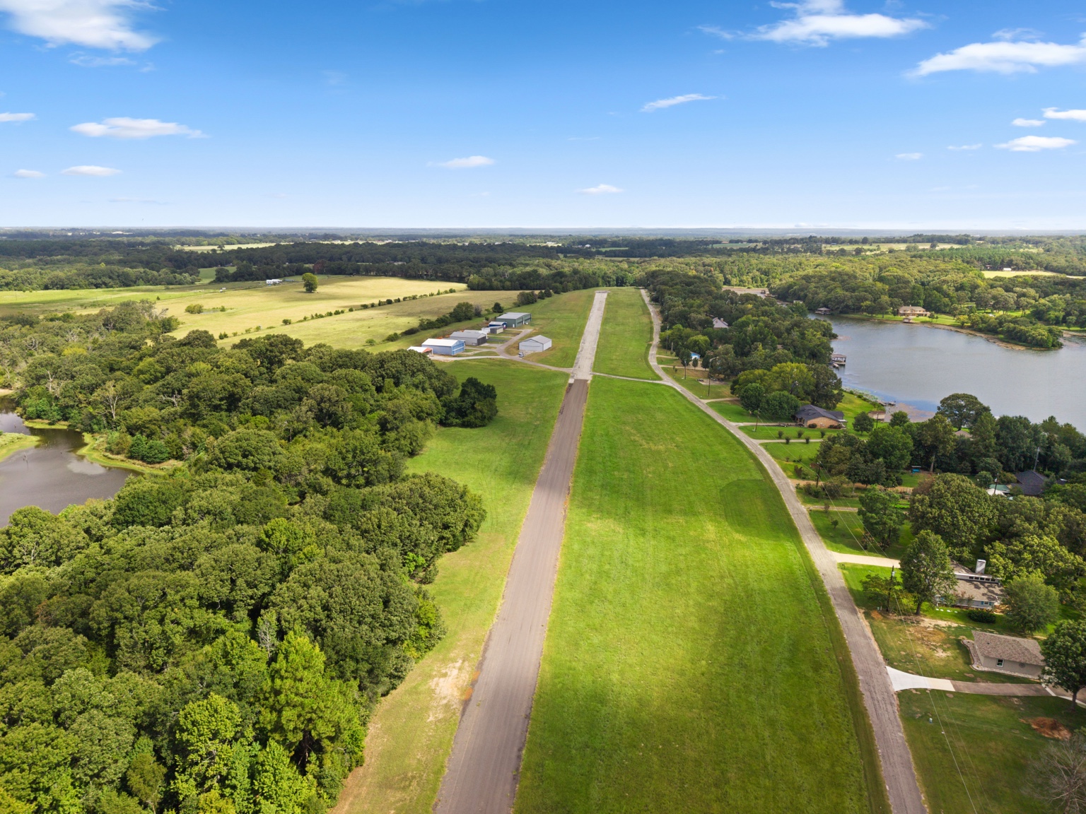 Aerial view looking straight down Echo Lake Airstrip with homes, trees and the lake beside the runway
