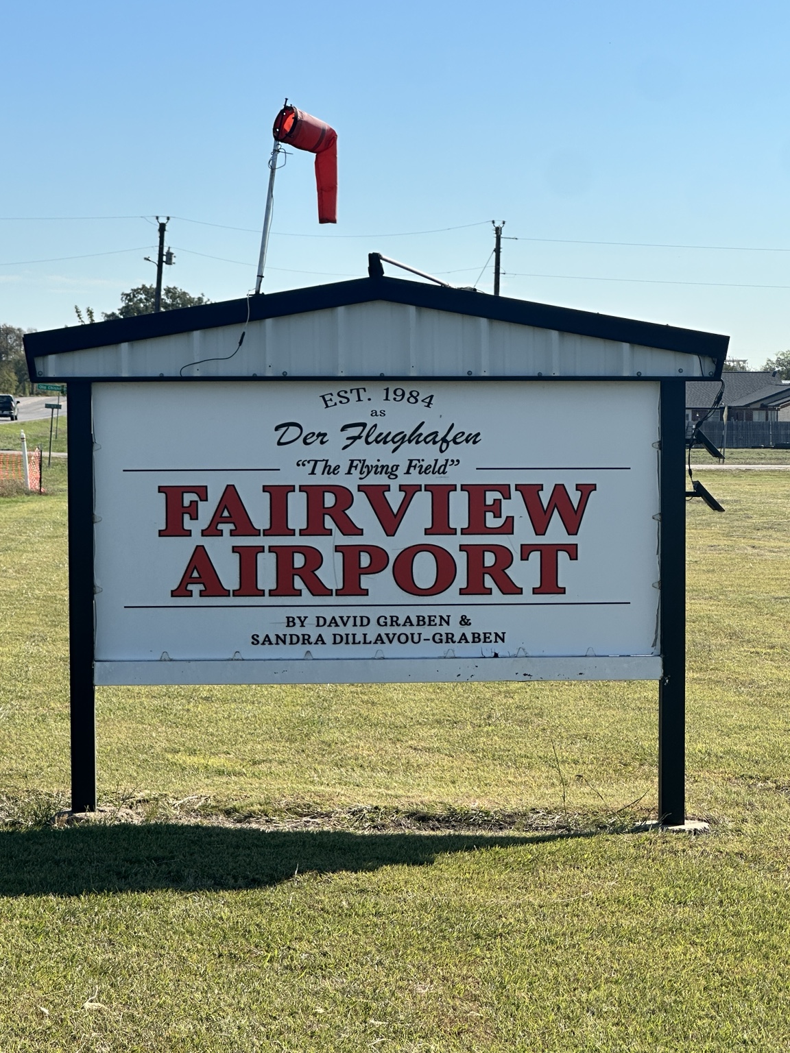 Fairview Airport entrance sign beneath a red windsock