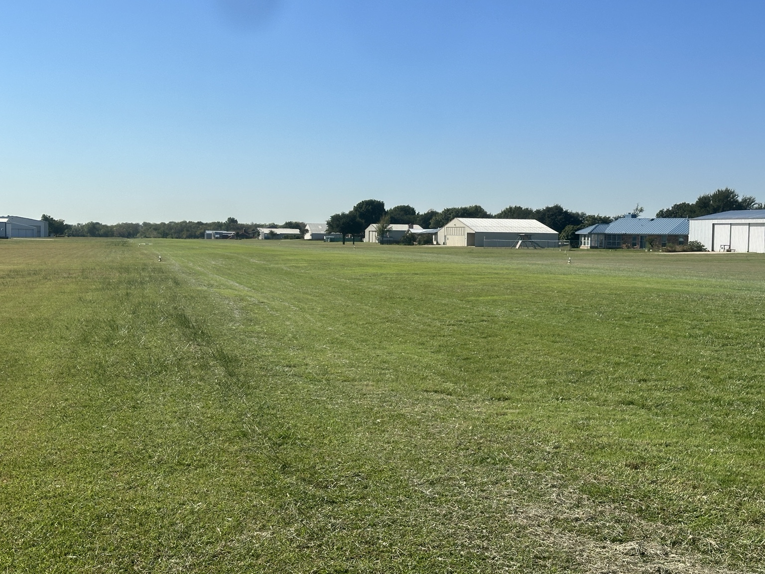 Homes and metal aircraft hangars lining Fairview Airport’s grass runway