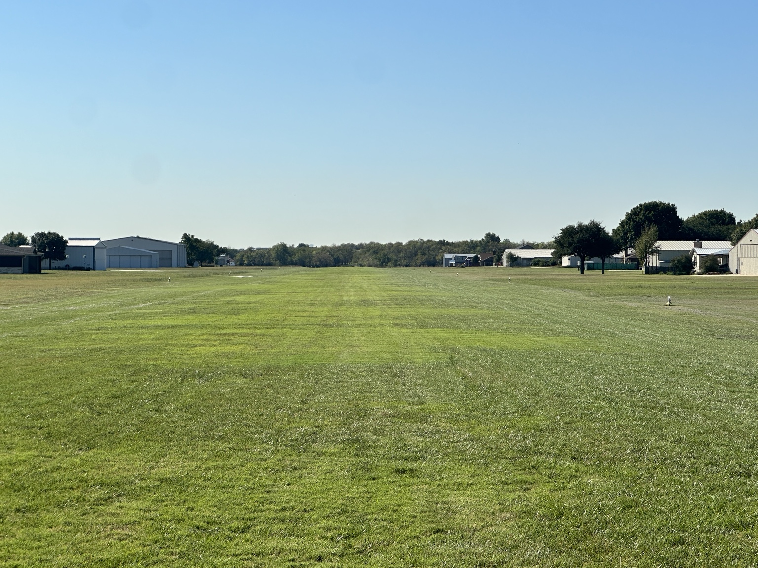 Grass runway at Fairview Airport with homes and hangars on both sides