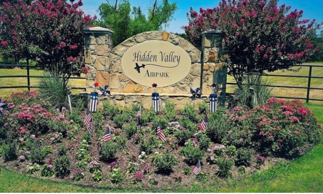 Hidden Valley Airpark entrance sign with flower bed and flags