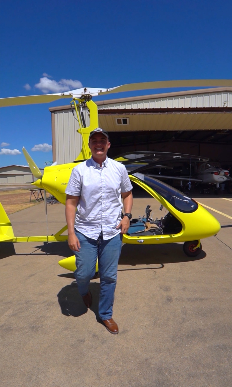 John Naugle standing beside a yellow gyrocopter outside a private hangar at Eagle’s Nest Estates