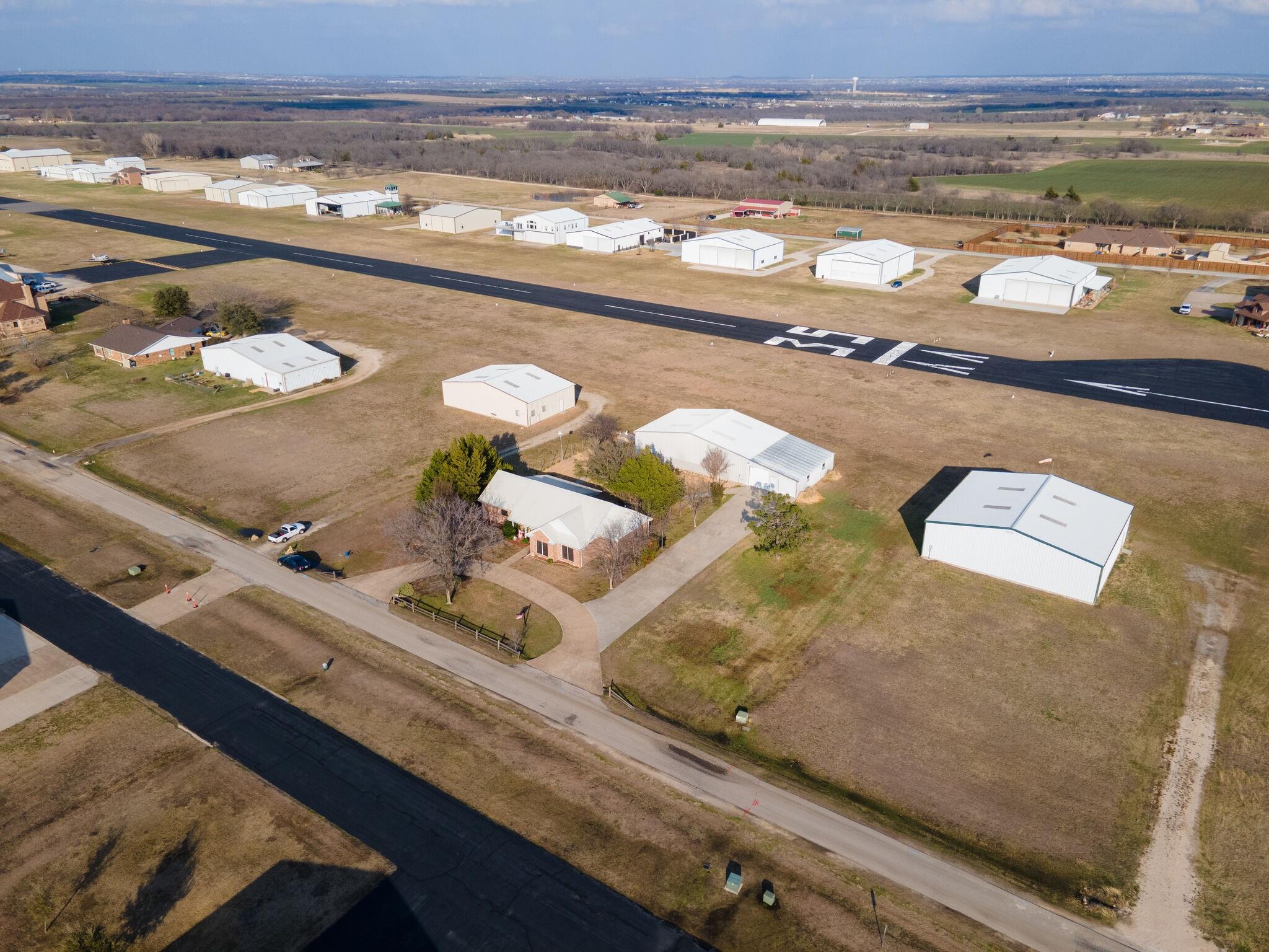 Aerial view of homes and aircraft hangars beside the runway at Propwash Airport