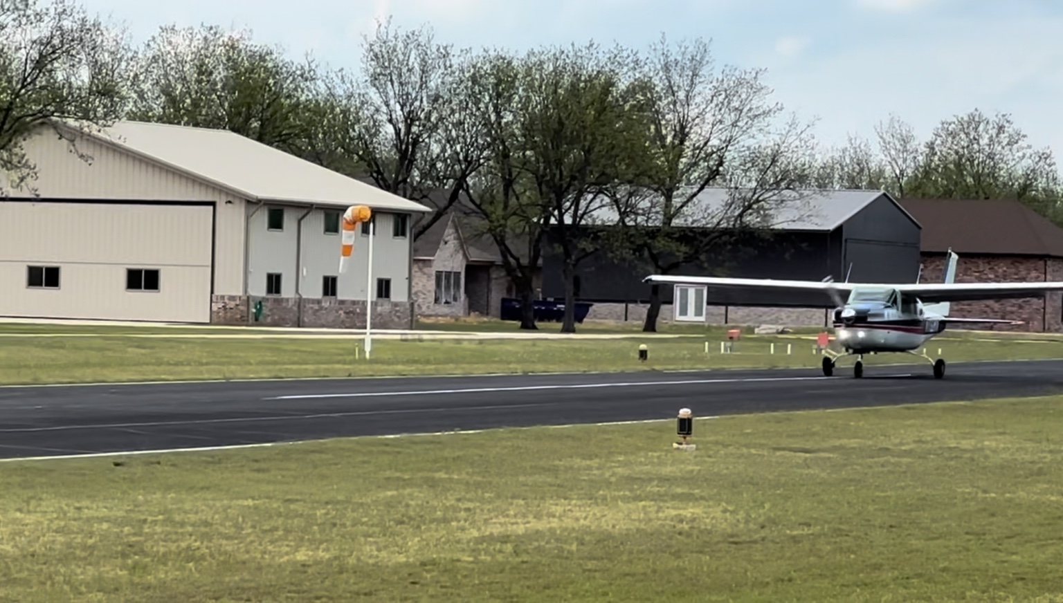 Light aircraft on the paved runway at The Landings with hangar homes behind it