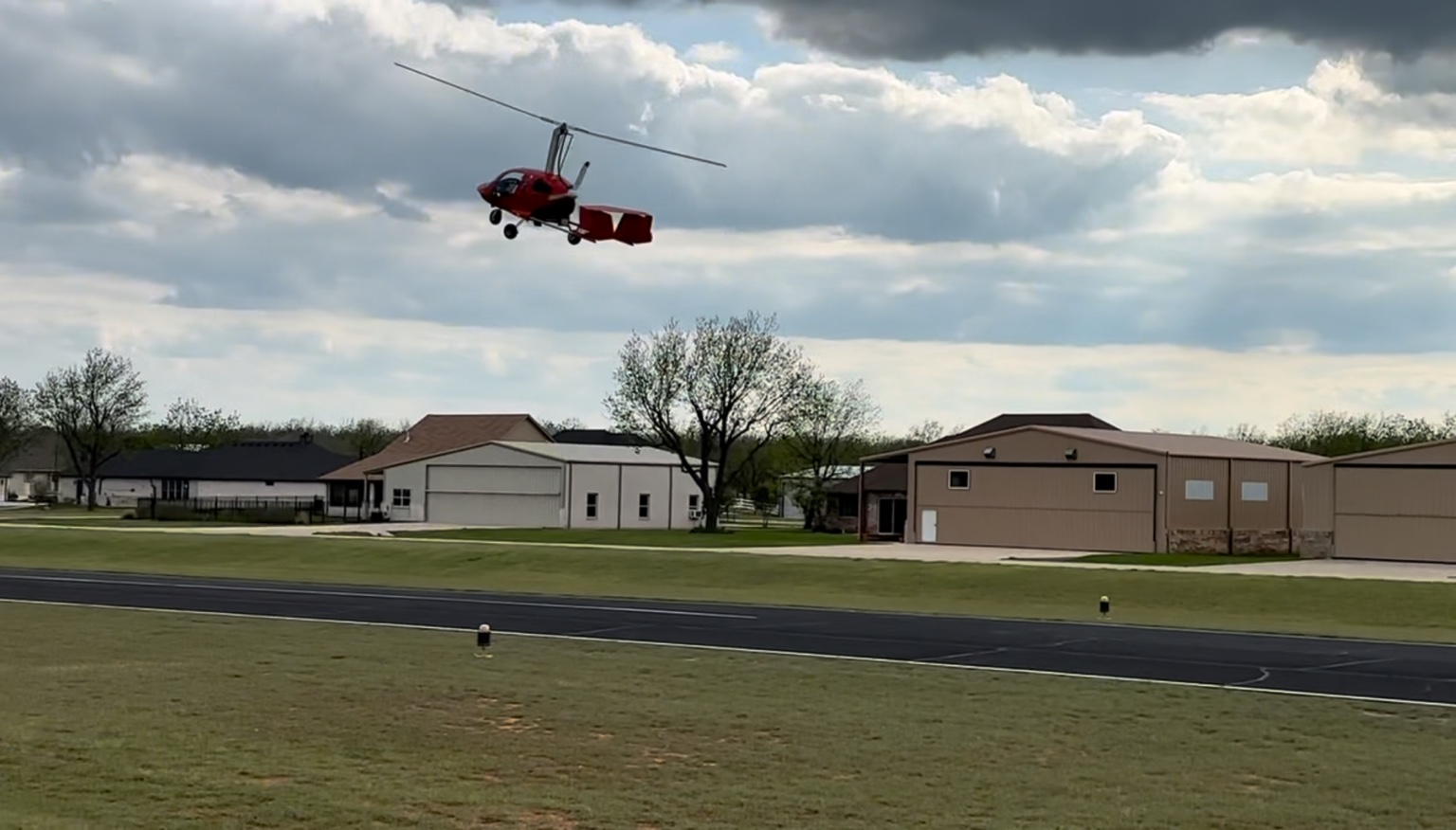 Gyrocopter flying above Runway 17/35 and hangar homes at The Landings